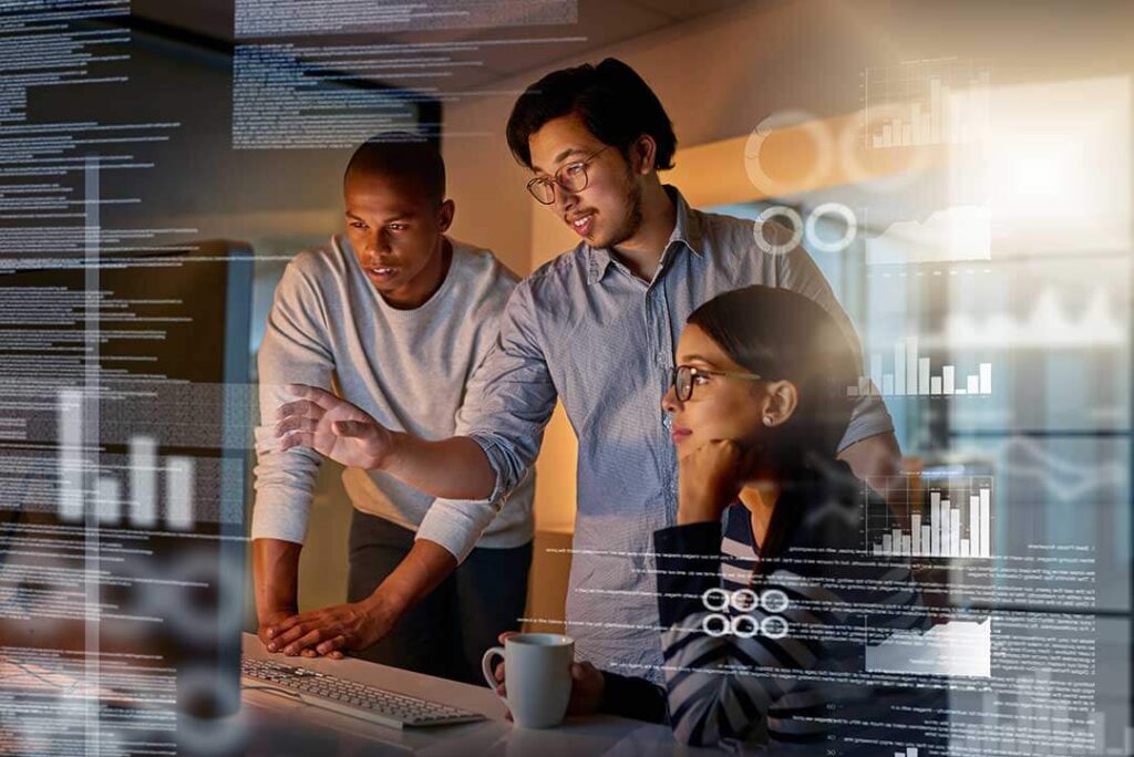 Three professionals collaborating around a computer screen, with transparent overlays of data visualisations, charts, and code. The image highlights teamwork and innovation in data-driven solutions, representing the integration of technology and analytics for renewable energy or sustainable development projects.